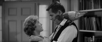 Movie still from “The Gazebo” (1959), directed by George Marshall – A man and a woman are holding each other in a room; Close Up shot, Low angle