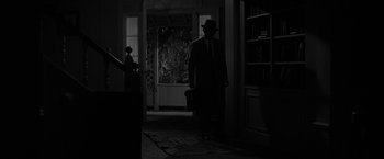 Movie still from “The Gazebo” (1959), directed by George Marshall – A man in a suit and a hat walking in a doorway; Wide shot, High angle