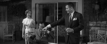 Movie still from “The Gazebo” (1959), directed by George Marshall – A man in a suit is giving a toast to another man in a suit and tie; Medium shot, Low angle