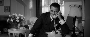Movie still from “The Gazebo” (1959), directed by George Marshall – A man sitting at a table talking on a phone; Close Up shot, High angle