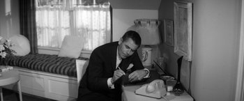Movie still from “The Gazebo” (1959), directed by George Marshall – A black and white photo of a man sitting at a desk; Medium shot, High angle