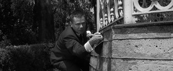 Movie still from “The Gazebo” (1959), directed by George Marshall – A black and white photo of a man leaning on a fence; Medium shot, Low angle