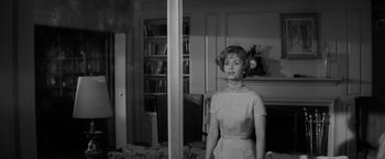 Movie still from “The Gazebo” (1959), directed by George Marshall – A black and white photo of a woman standing in front of a mirror; Medium shot, Low angle
