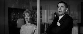 Movie still from “The Gazebo” (1959), directed by George Marshall – An older woman standing next to a man in a room; Medium shot, Low angle