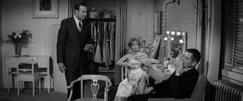 Movie still from “The Gazebo” (1959), directed by George Marshall – A man and a woman in front of a dressing room; Medium shot, High angle