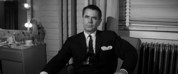 Movie still from “The Gazebo” (1959), directed by George Marshall – Black and white photograph of a man wearing a suit and tie; Close Up shot, Over the shoulder angle