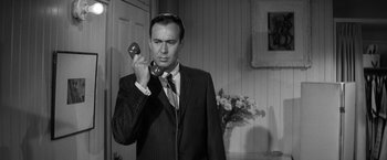 Movie still from “The Gazebo” (1959), directed by George Marshall – A black and white photo of a man holding a phone up to his ear; Close Up shot, Low angle