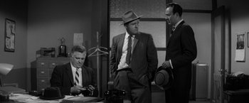 Movie still from “The Gazebo” (1959), directed by George Marshall – A group of men standing next to each other in a room; Medium shot, Over the shoulder angle