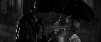 Movie still from “The Gazebo” (1959), directed by George Marshall – A man holding an umbrella over a woman's head; Close Up shot, Over the shoulder angle