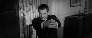 Movie still from “The Gazebo” (1959), directed by George Marshall – A black and white photo of a man in a suit and tie; Medium shot, Low angle