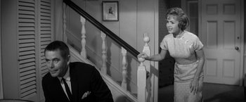 Movie still from “The Gazebo” (1959), directed by George Marshall – A young woman holding a railing while a man stands on the stairs; Medium shot, Over the shoulder angle