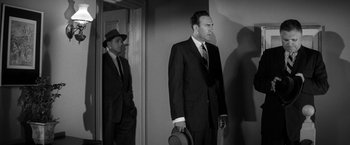 Movie still from “The Gazebo” (1959), directed by George Marshall – A man in a suit and hat standing next to another man in a suit and hat; Medium shot, Low angle