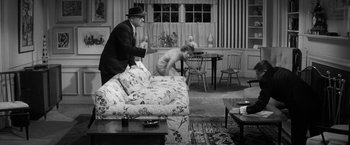 Movie still from “The Gazebo” (1959), directed by George Marshall – A man and a woman in a living room playing a video game; Wide shot, High angle