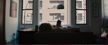 Movie still from “The Girlfriend Experience” (2009), directed by Steven Soderbergh – A woman sitting on a couch in front of a large window; Wide shot, Low angle