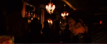 Movie still from “The Girlfriend Experience” (2009), directed by Steven Soderbergh – A man sitting at a table in front of chandeliers; Medium shot, Over the shoulder angle