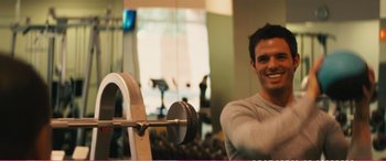 Movie still from “The Girlfriend Experience” (2009), directed by Steven Soderbergh – A man is smiling in front of a barbell in a gym; Medium shot, Over the shoulder angle