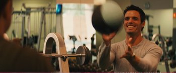 Movie still from “The Girlfriend Experience” (2009), directed by Steven Soderbergh – A man holding a weight in front of a barbell in a gym; Medium shot, Over the shoulder angle