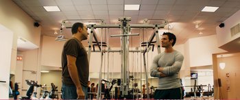 Movie still from “The Girlfriend Experience” (2009), directed by Steven Soderbergh – Two men are standing in a gym talking to each other; Medium shot, Over the shoulder angle