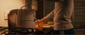 Movie still from “The Girlfriend Experience” (2009), directed by Steven Soderbergh – A person is pouring orange juice into a juicer; Medium shot, High angle