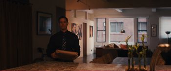 Movie still from “The Girlfriend Experience” (2009), directed by Steven Soderbergh – A man standing in front of a counter holding a piece of paper; Medium shot, Over the shoulder angle
