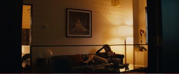 Movie still from “The Girlfriend Experience” (2009), directed by Steven Soderbergh – A woman laying on a couch in front of a picture; Wide shot, Low angle