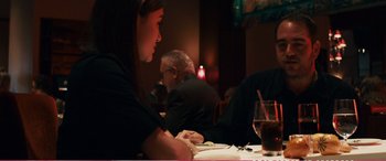 Movie still from “The Girlfriend Experience” (2009), directed by Steven Soderbergh – A woman sitting at a table with a glass of wine; Medium shot, Over the shoulder angle