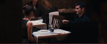 Movie still from “The Girlfriend Experience” (2009), directed by Steven Soderbergh – A person sitting at a table with a glass of water; Medium shot, Over the shoulder angle