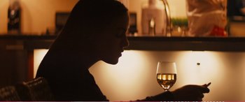 Movie still from “The Girlfriend Experience” (2009), directed by Steven Soderbergh – A woman sitting in front of a glass of wine; Close Up shot, Over the shoulder angle