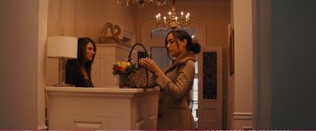 Movie still from “The Girlfriend Experience” (2009), directed by Steven Soderbergh – A woman looking at a purse while holding a cell phone; Medium shot, Over the shoulder angle