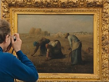 Movie still from “The Gleaners & I” (2000), directed by Agnès Varda – A person taking a picture of a painting; Medium shot, Over the shoulder angle