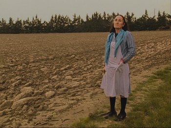 Movie still from “The Gleaners & I” (2000), directed by Agnès Varda – A woman standing in the middle of an empty field; Wide shot, High angle