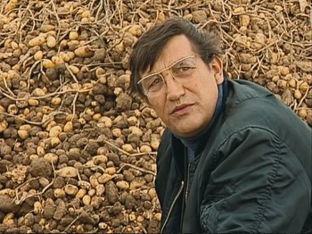 Movie still from “The Gleaners & I” (2000), directed by Agnès Varda – A man in a field of nuts with glasses on; Close Up shot, Low angle
