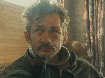 Movie still from “The Gleaners & I” (2000), directed by Agnès Varda – A person wearing a jacket and smoking; Close Up shot, High angle