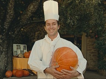Movie still from “The Gleaners & I” (2000), directed by Agnès Varda – A man in a chef's hat holding a pumpkin; Medium shot, High angle