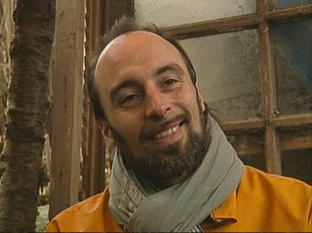 Movie still from “The Gleaners & I” (2000), directed by Agnès Varda – A man with a beard wearing an orange jacket and a gray scarf; Close Up shot, Low angle
