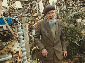 Movie still from “The Gleaners & I” (2000), directed by Agnès Varda – An old man standing in front of a pile of junk; Medium shot, Low angle