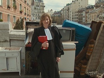 Movie still from “The Gleaners & I” (2000), directed by Agnès Varda – A woman dressed as a judge standing in front of a pile of garbage; Wide shot, High angle