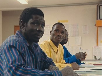 Movie still from “The Gleaners & I” (2000), directed by Agnès Varda – A group of men sitting at a table in front of papers; Medium shot, High angle