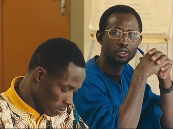 Movie still from “The Gleaners & I” (2000), directed by Agnès Varda – Two men sitting in front of each other and one is holding a pen; Close Up shot, Over the shoulder angle