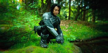 Movie still from “Altered Carbon” (2018), created by Laeta Kalogridis – A man dressed in a costume kneeling on the ground; Medium shot, Low angle