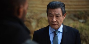 Movie still from “Altered Carbon” (2018), created by Laeta Kalogridis – An older man in a suit and a tie; Close Up shot, Over the shoulder angle