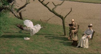 Movie still from “The Go-Between” (1971), directed by Joseph Losey – An old man sitting on a bench under an umbrella; Wide shot, Overhead angle