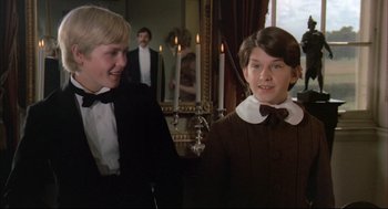 Movie still from “The Go-Between” (1971), directed by Joseph Losey – Two young men in tuxedos standing next to each other in front of candles; Medium shot, Over the shoulder angle