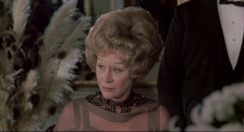 Movie still from “The Go-Between” (1971), directed by Joseph Losey – An older woman in a brown dress and a black and white neck scarf; Close Up shot, Over the shoulder angle