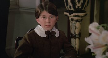 Movie still from “The Go-Between” (1971), directed by Joseph Losey – A young boy in a brown coat and a bow tie; Close Up shot, High angle