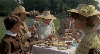 Movie still from “The Go-Between” (1971), directed by Joseph Losey – A group of people sitting at a table with plates of food on it; Medium shot, High angle
