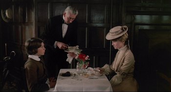 Movie still from “The Go-Between” (1971), directed by Joseph Losey – Two women and a man sitting at a dinner table; Medium shot, High angle
