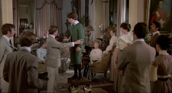 Movie still from “The Go-Between” (1971), directed by Joseph Losey – A group of people gathered around a man in a green suit; Wide shot, Over the shoulder angle