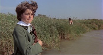 Movie still from “The Go-Between” (1971), directed by Joseph Losey – A young boy standing next to a body of water; Medium shot, Over the shoulder angle