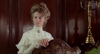 Movie still from “The Go-Between” (1971), directed by Joseph Losey – A woman in a white dress sitting in a chair; Medium shot, Low angle